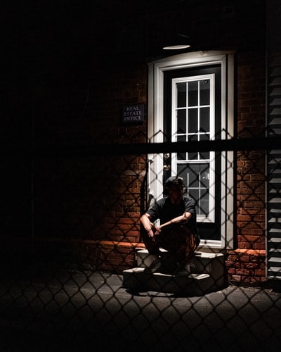 穿着红衫的男人坐在棕色的木凳上